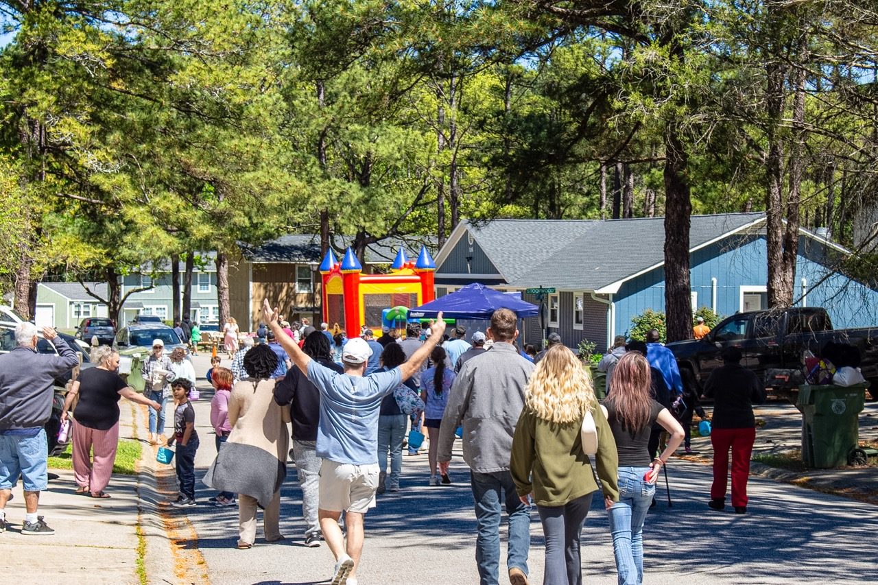 Neighbors and families walking down a Beatty Downs street toward a bounce house at Family and Alumni Day